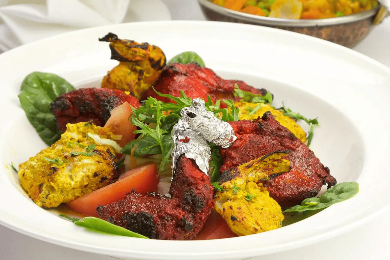 Indian chicken appetisers plated with fresh herbs and dipping sauces