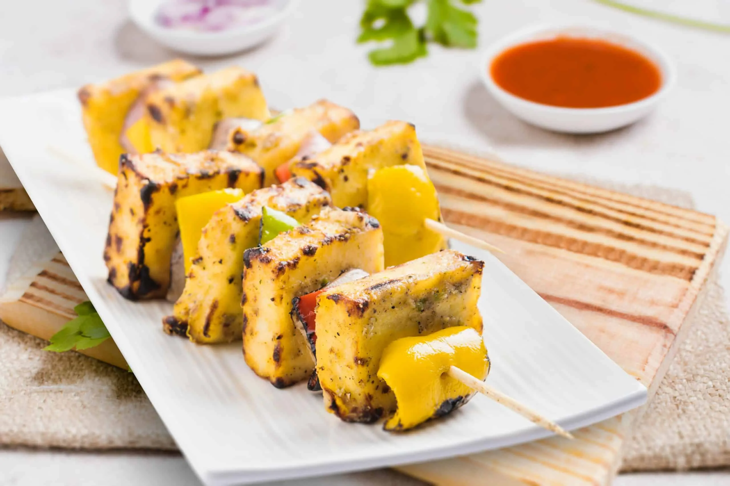 Skewers of grilled paneer tikka with capsicum and onion